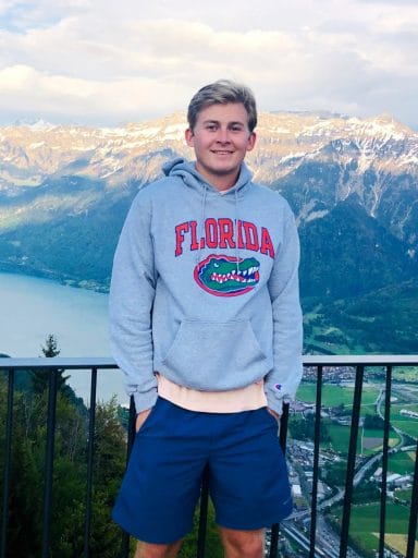 Austin Vetter stands at a railing overlooking a picturesque valley, lake and mountains