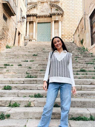 Jade Starkey on vacation in front of steps leading up to a block building with columns