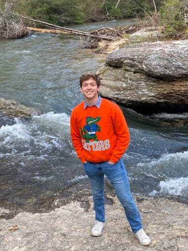 Alessandro Perugini stands on rock beside a river