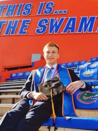 Jack Boyd in graduation attire sits in the UF stadium