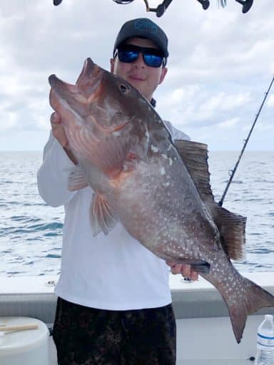 Joseph Cowan holds a grouper on a boat