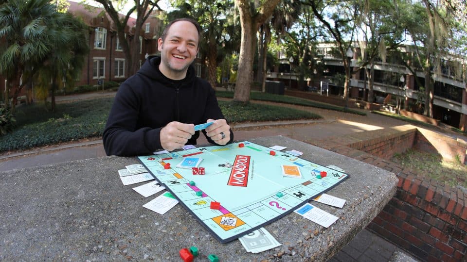 Paul Madsen sets up a monopoly game in the courtyard by Bryan Hall and Stuzin Hall