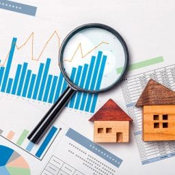 Charts and tables with a magnifying glass and wood block buildings laid on top