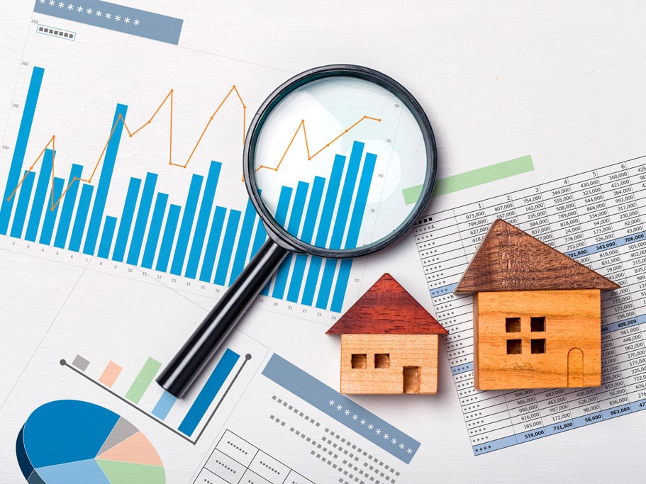 Charts and tables with a magnifying glass and wood block buildings laid on top