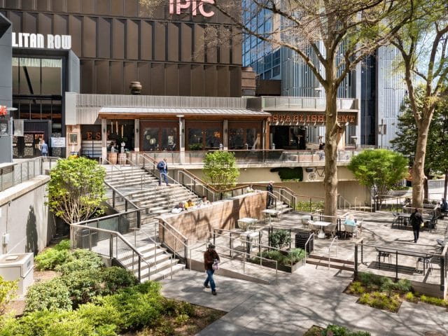 Outdoor space with tables surrounded by establishments on an upper level