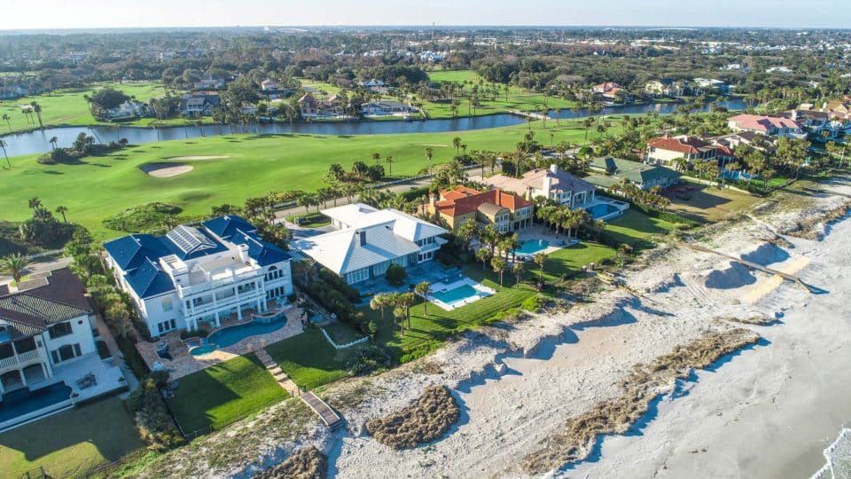 Beach homes lined along the shore and other neighborhoods in the background along a waterway