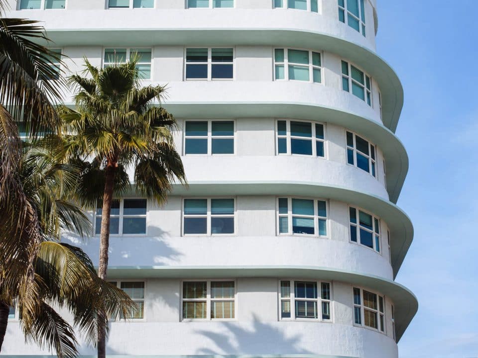 An apartment building with palm trees beside it