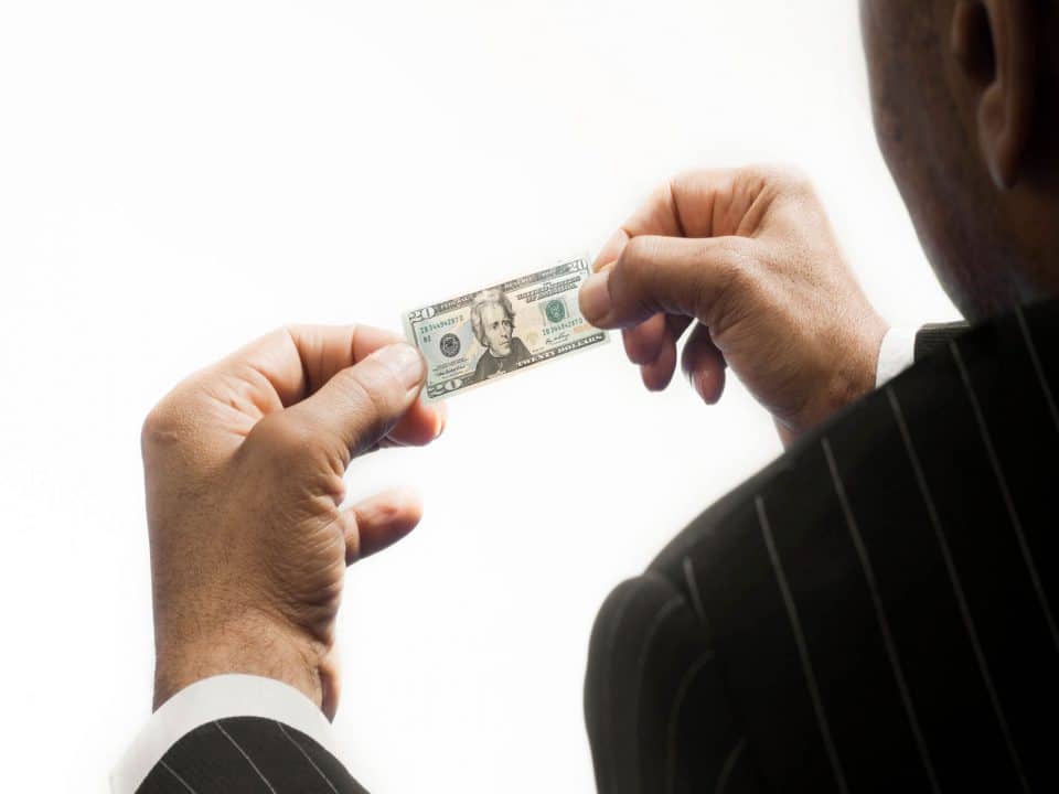 A man holds a tiny twenty dollar bill