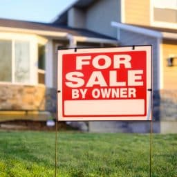 A for sale by owner sign in front of a residence