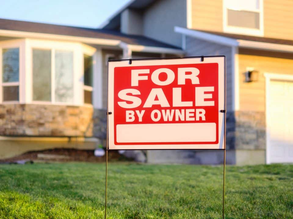 A for sale by owner sign in front of a residence