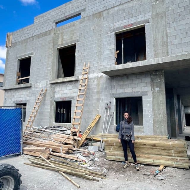 Natalie Duran stands in front of a residential building under construction in Little Havana