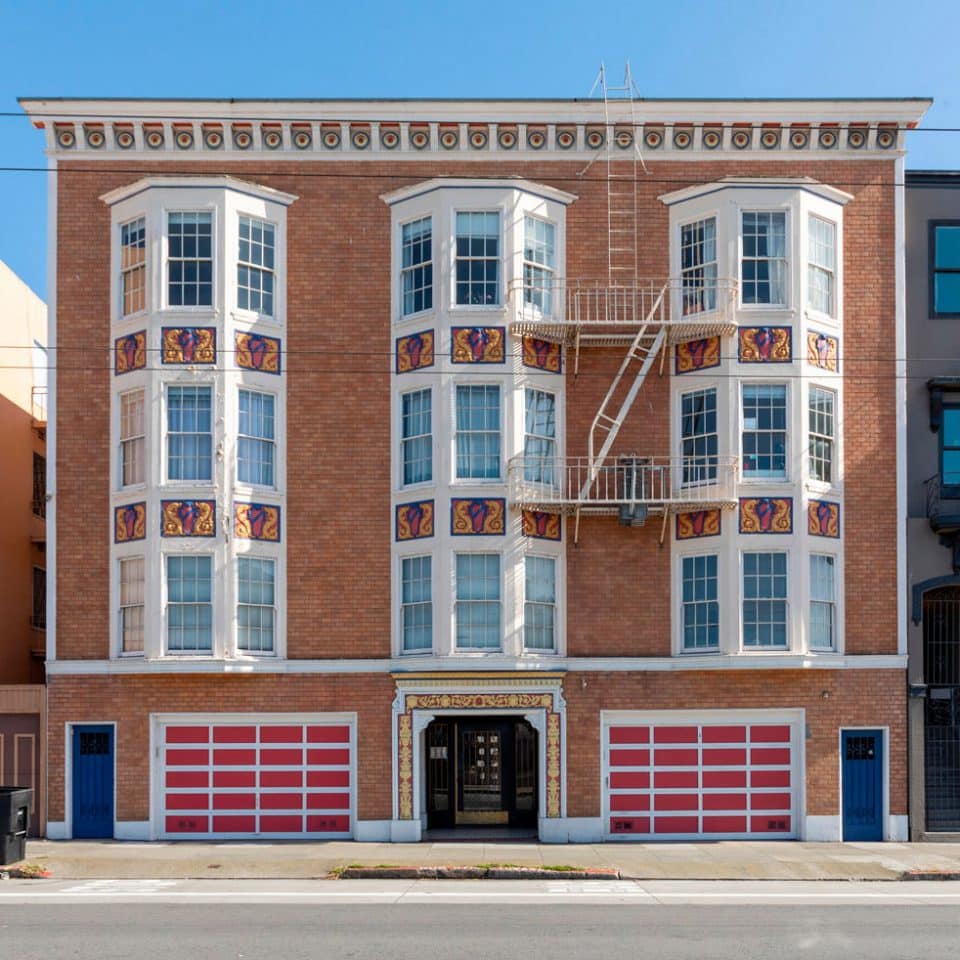 A brick rental building with three floors above the two garages and entry door