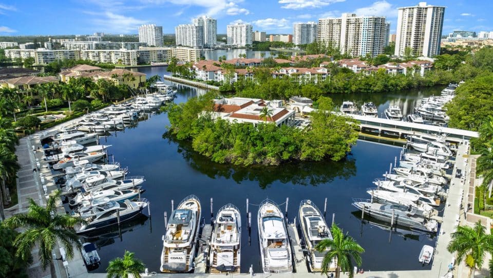 Aerial photo of Williams Island Marina in Aventura, Florida, full of boats with buildings and blue skies in the background