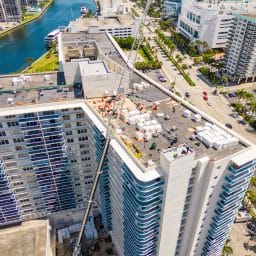 Workers on top of a tall condo as materials and supplies are brought up by crane in Hollywood Beach, FL