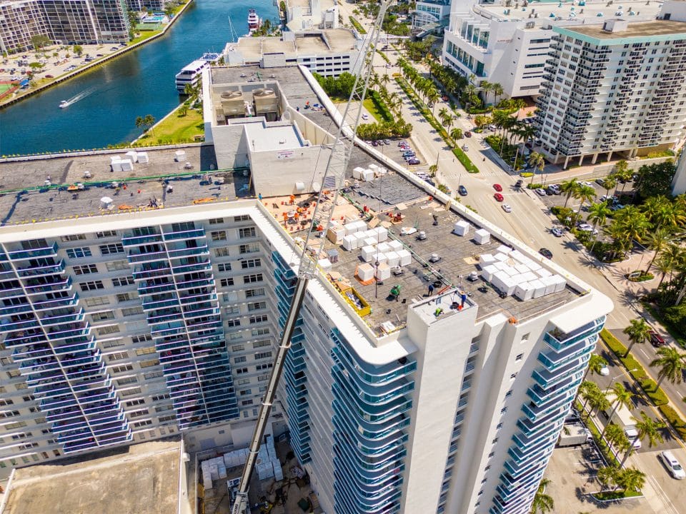 Workers on top of a tall condo as materials and supplies are brought up by crane in Hollywood Beach, FL