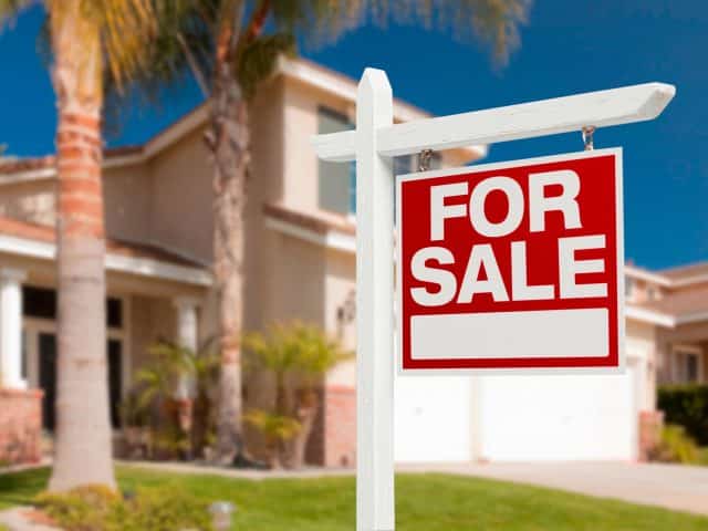 A red for sale sign in front of a house