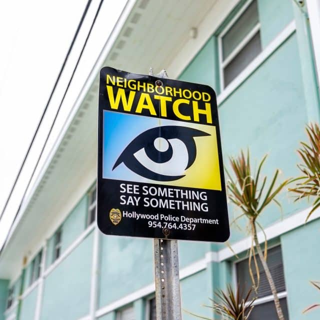 A neighborhood watch sign with an eye symbol and the words, see something, say something, Holleywood Police Department 954.764.4357