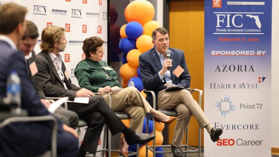 A man speaks into a microphone during a panel discussion at the FIC