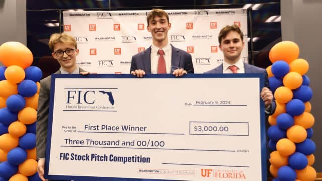 Three winners of the 2024 FIC Stock Pitch Competition hold a giant check for ,000