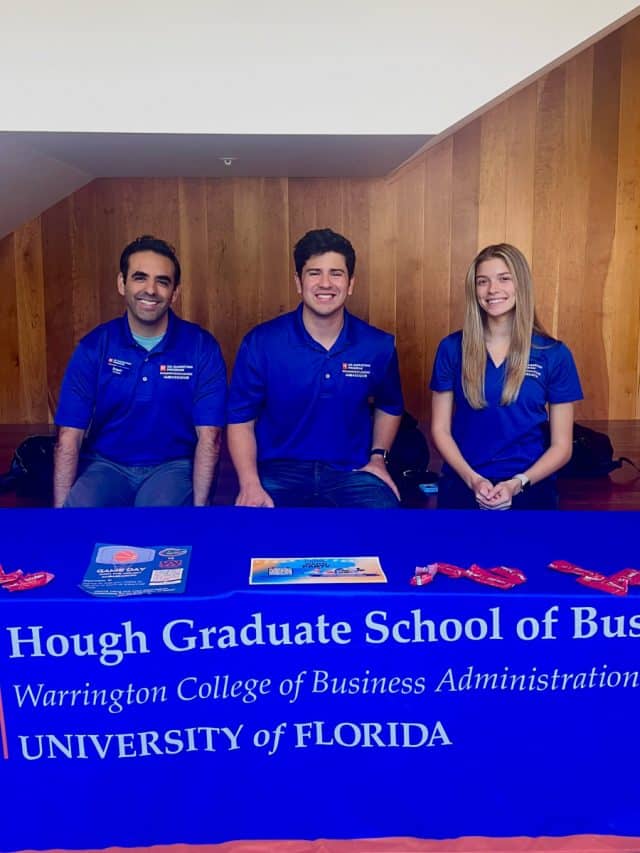 Three ambassadors sit behind a table in Hough Hall with materials spread out on it