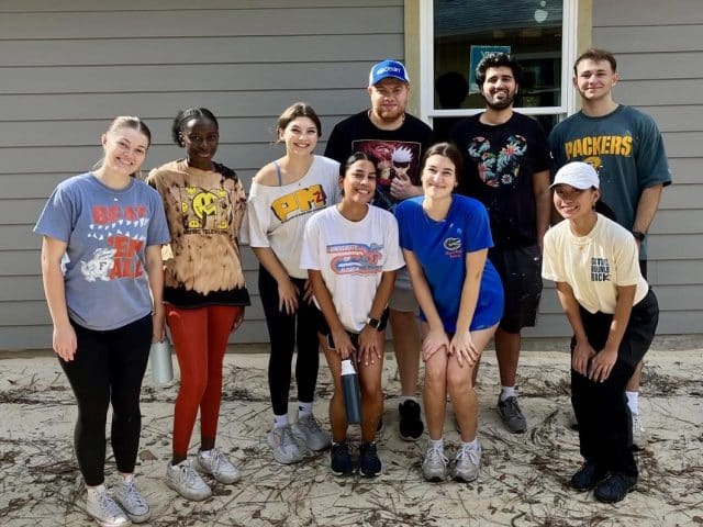 A group of Hough Graduate ambassadors pose in front of a newly built home at Habitat for Humanity Service Day