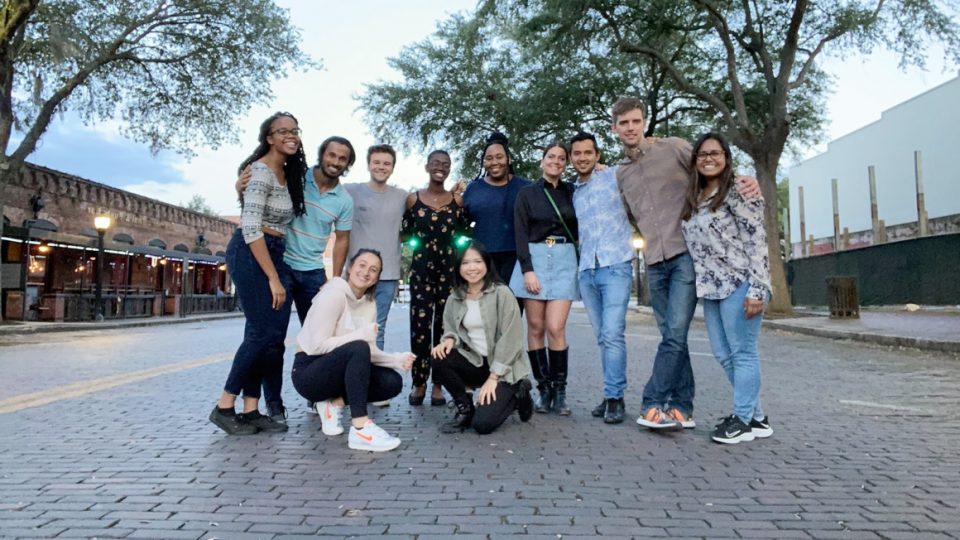 A group of students stand in a downtown brick street in the evening