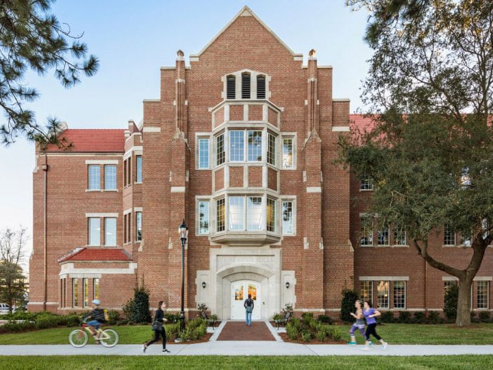 The north side of Heavener Hall as students walk, jog and ride bike on the sidewalk