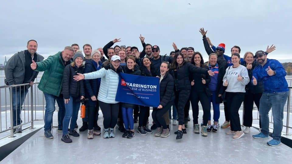 A group of MBAs holding a Warrington College of Business outside in Oslo.