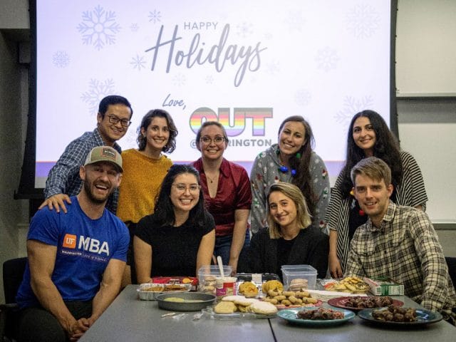 Students gather around a table with a variety of cookies displayed on it