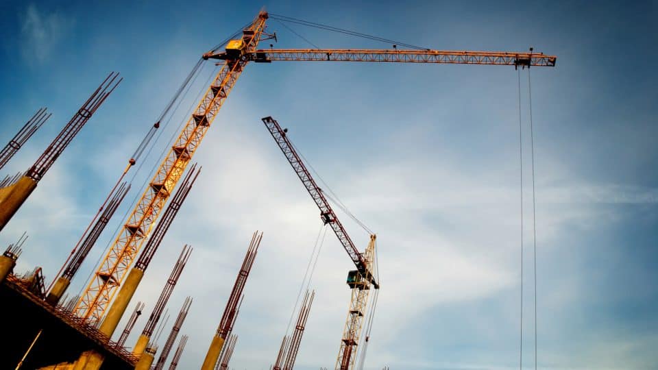 The skyward view of two construction cranes on a job site