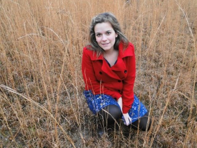 Camila Pazos kneeling in tall, wild grass