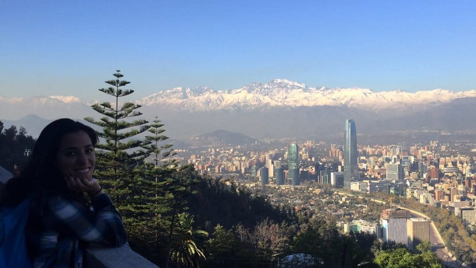 Student smiles with Santiago skyline and mountains in the background