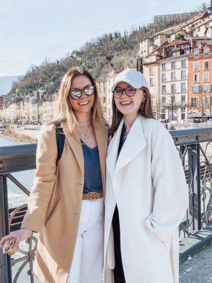 Two students outside in front of landscape in Grenoble, France during winter.