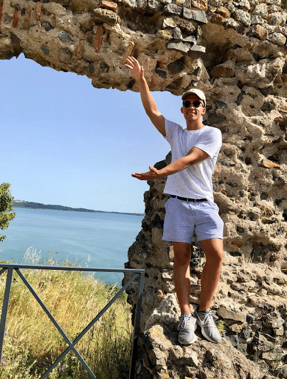 Student standing in front of Lake Bracciano in Italy, doing Gator Chomp