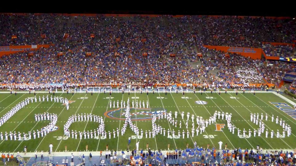 Fans fill the stadium at a Gator football game where the marching band is spelling out Gators on the field, photo credit UF College of the Arts