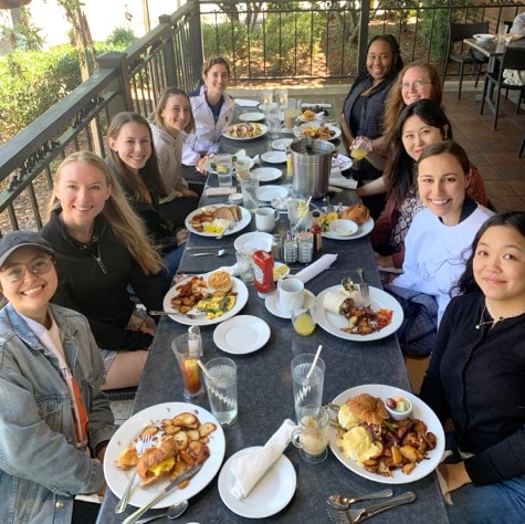 A group of young women enjoy breakfast together on an outdoor patio