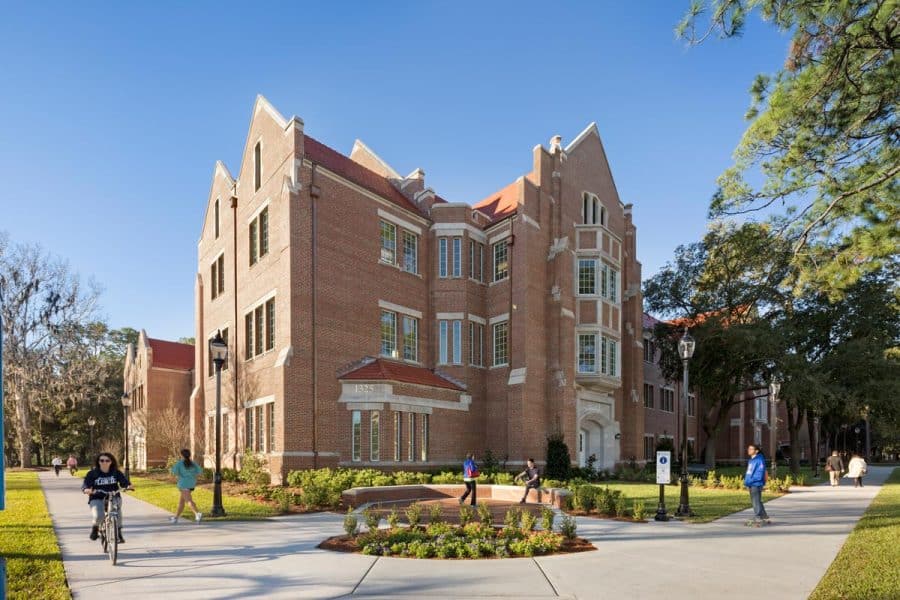 Heavener Hall with students walking, running, biking and skating by
