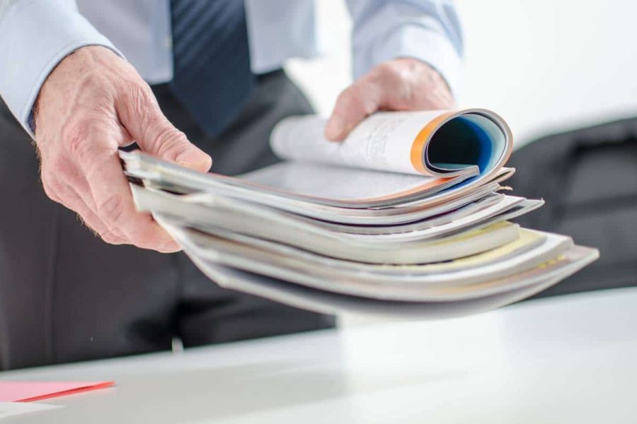 A man holding a stack of publications with the top one open