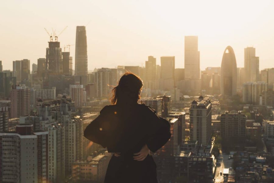 A woman on a rooftop looking at city buildings against the sunlight