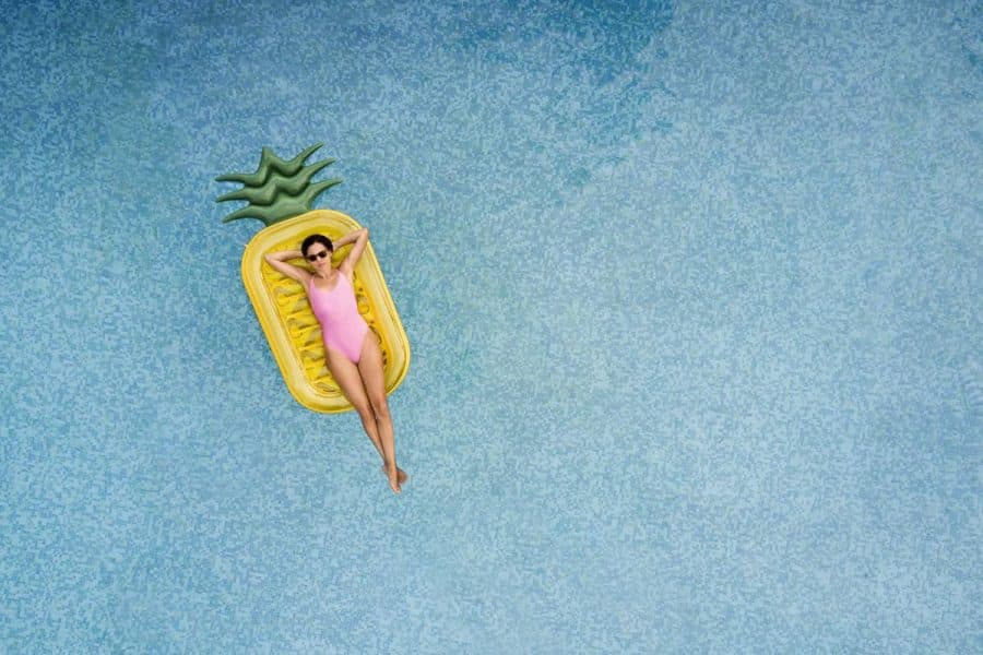 Carefree woman reclines on an inflatable pineapple in a pool