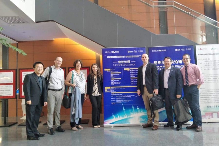 Seven faculty members from Warrington's management department pose in front of a conference sign in China