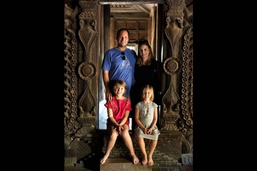 Aaron and Carly Topol pose for a photo in an old building in China with their two daughters