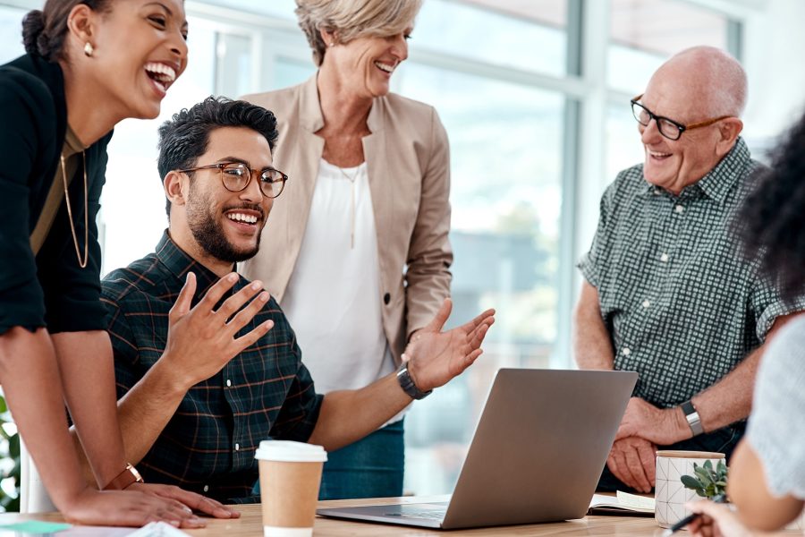 A group of businesspeople working together on a laptop in an office