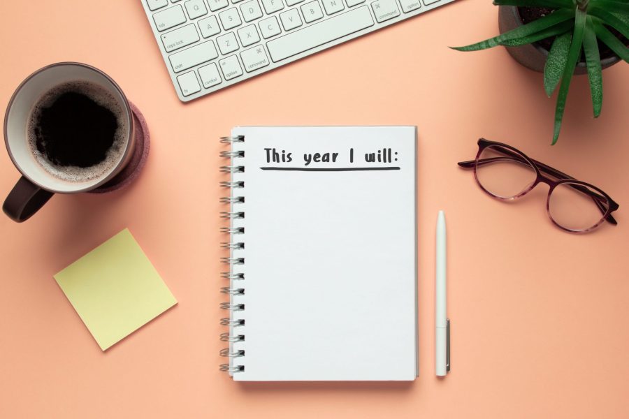 Stock photo of new year notebook with list of resolutions and objects on pink background