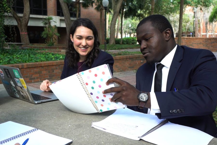 One female and one male student looking over class notes sitting outside at a picnic table