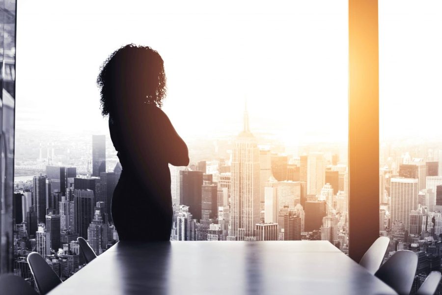 Silhouetted shot of a young businesswoman looking at a cityscape from an office window
