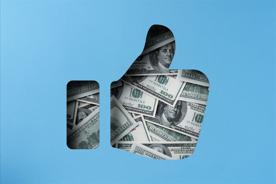 American one hundred dollar bills showing through a paper cutout of a thumbs up icon