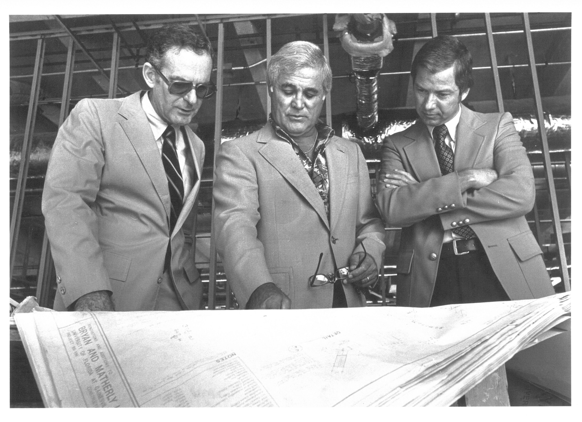 Hadley Schaefer, Robert Lanzillotti and John Simmons look down at plans for buildings on the Warrington College of Business campus.