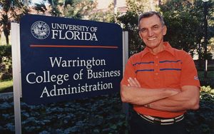 Al Warrington stands next to the Warrington College of Business sign