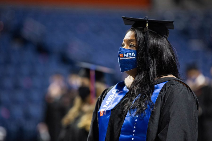 Young Black woman wearing commencement regalia stands during a graduation ceremony.